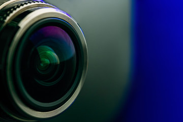 Fototapeta na wymiar Camera lens with blue backlight. Side view of the lens of camera on blue background. Blue camera Lens close Up.