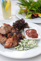 pieces of kebab with ketchup and onions on a plate