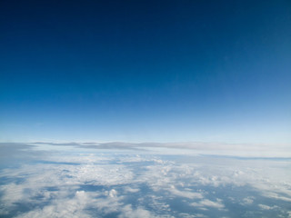 Fototapeta na wymiar Clear blue sky with calming bed of white clouds from a flight in Spring or Summer