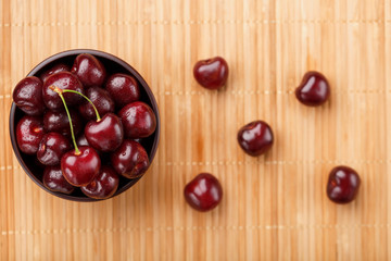 Ripe and juicy cherry berries on a wooden background in a brown cup