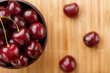 Ripe and juicy cherry berries on a wooden background in a brown cup
