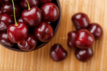 Ripe and juicy cherry berries on a wooden background in a brown cup