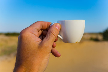 people hand take cofee cup on the sandy desert background