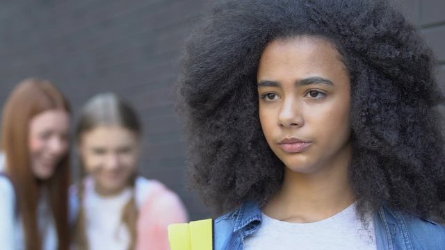 Cruel teen girls laughing at biracial female student, school bullying, racism