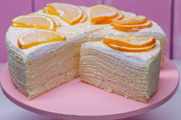 Home made cake from pancakes with white cream, beautifully decorated with oranges on top.