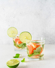 Glass of cool infused water with fresh grapefruit, lime and mint, (lemonade, cocktail). Detox drink, health care, fitness, diet concept.