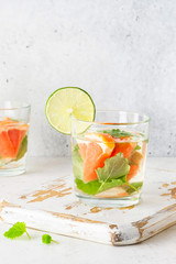 Glass of cool infused water with fresh grapefruit, lime and mint, (lemonade, cocktail). Detox drink, health care, fitness, diet concept.