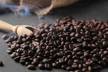 Roasted coffee grains and a wooden spoon on a black background. close-up. Rabusta, Arabica.