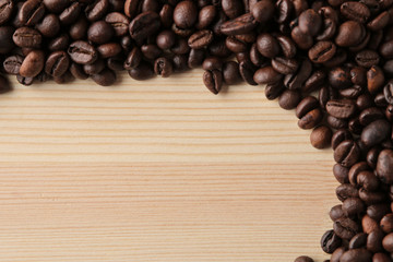 roasted coffee beans on a natural wooden table. Frame of coffee beans Robusta, Arabica. top view. space for text