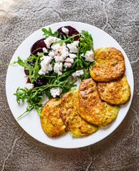 Pancakes with greek salad on white plate