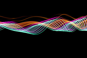 Long exposure photograph of neon purple, green and metallic gold colour in an abstract swirl pattern against a black background. Light painting photography.