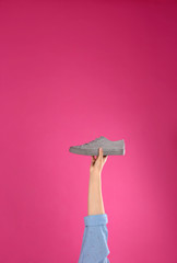 Young woman holding comfortable shoe on pink background, closeup