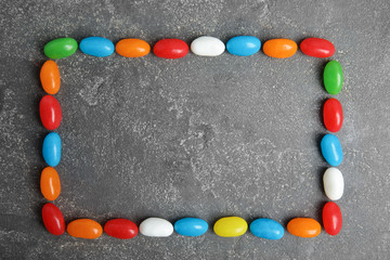 Frame of jelly beans on stone background, top view. Space for text