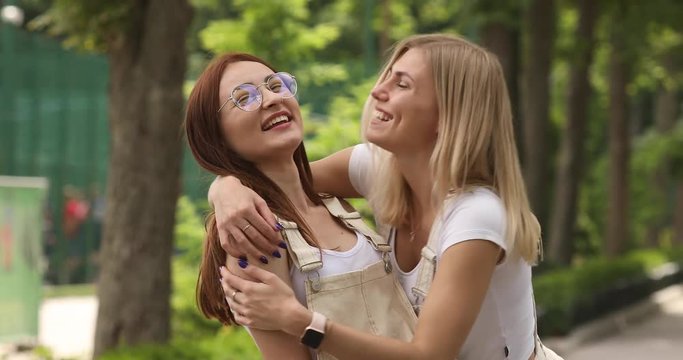 Outdoor lifestyle portrait of two best friends hipster girls wearing stylish bright outfits, going crazy and having great time together. Laughing and send kiss, lovely friends.