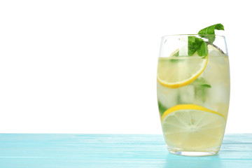 Glass of refreshing lemonade with mint on blue wooden table against white background. Summer drink