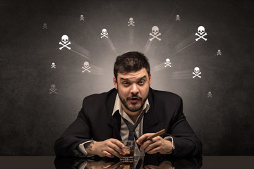 Loser drunk man sitting at table with skulls concept around