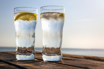 Wooden table with glasses of refreshing lemon drink on hot summer day outdoors, space for text