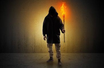 Ugly scary man with burning flambeau walking in an empty space