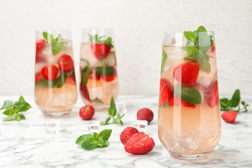 Glasses of refreshing drink with strawberry and mint on marble table, space for text