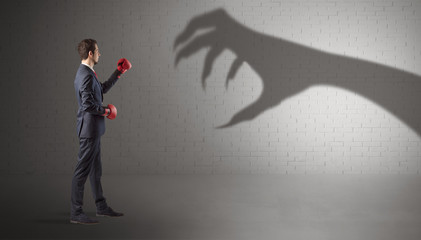 Tiny businessman fighting with scary hand shadow