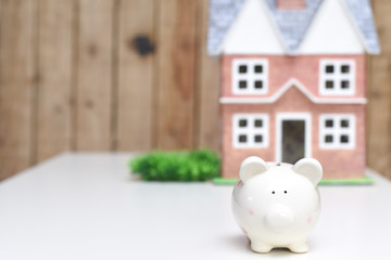 Piggy bank and new home, concept of saving money to pay for mortgage of new property