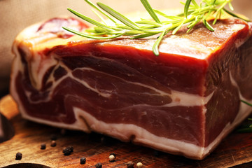 Italian prosciutto crudo or jamon with rosemary. Raw ham on wooden board