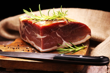 Italian prosciutto crudo or jamon with rosemary. Raw ham on wooden board