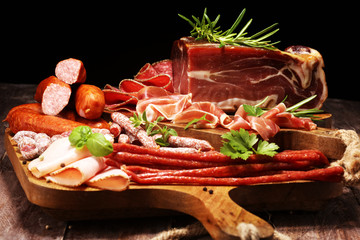 Food tray with delicious salami, pieces of sliced ham, sausages,salad and vegetable. Meat platter with selection