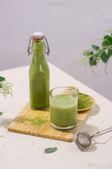 Matcha green tea latte in bottle and cup glass on white background