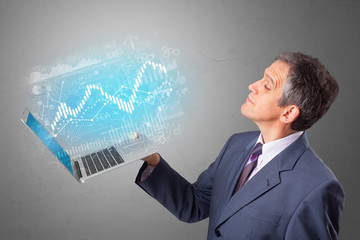 Man holding laptop projecting financial information, diagrams and charts