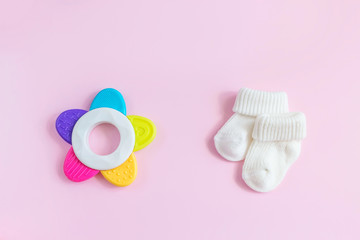 Baby accessories for newborns: socks and toy on  pink background. Motherhood concept. Top view, flat lay composition.