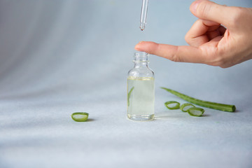 Dropper glass bottle with pipette Drop liquid essences with aloe vera dripping on woman's hand