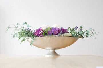 bouquet of green white and purple flowers in a silver metal bowl on a table bucket white background