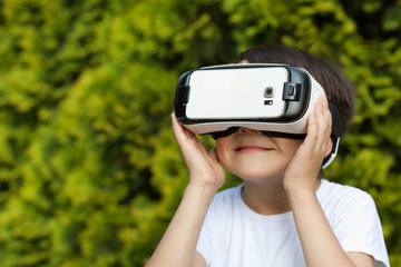 Cute little boy using VR glasses outdoors in a park - Blogger testing augmented reality goggles concept - Gamer exulting during 3D video game playing