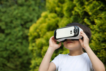 Cute little boy using VR glasses outdoors in a park - Blogger testing augmented reality goggles concept - Gamer exulting during 3D video game playing