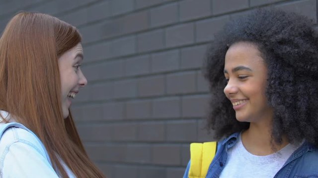 Cruel teenage girls mocking classmate passing by, malicious rumors, bullying