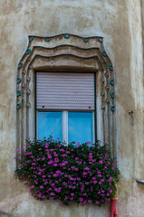 Fototapeta na wymiar Little pink flowers decorating a window. Building facade.