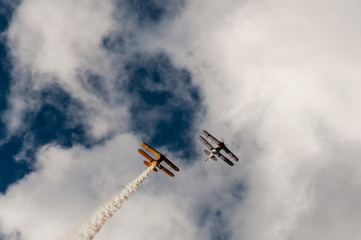 Aerobatics planes flying in the sky with clouds in the background