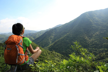 Successful young woman backpacker enjoy the view on spring forest mountain cliff edge