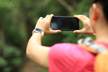 Woman hiker using smartphone taking pictures on hiking travel