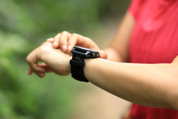 Woman hiker checking on sportswatch on hiking travel