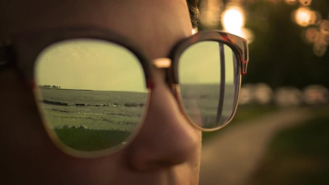 Millennial hipster fashionista puts on sunglasses in summer and stares at the ocean