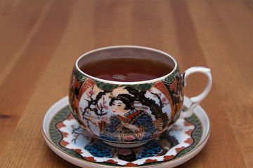 Fototapeta premium Chinese Cup with tea on a saucer. On a wooden table.