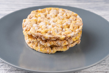 Three dried corn tortillas on a gray plate, on a white wooden table
