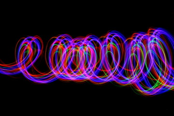 Long exposure photograph of neon multi colour in an abstract swirl parallel lines pattern against a...