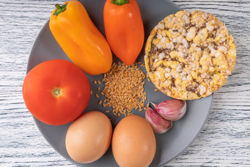 garlic, pepper, tomato, flax seeds, chicken eggs, corn tortillas on a gray plate