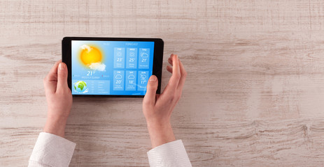 Man hand checking weekly weather forecast on tablet