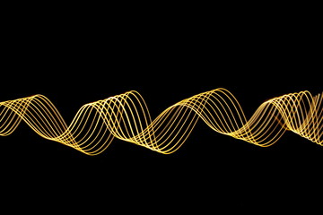 Long exposure photograph of neon gold colour in an abstract swirl parallel lines pattern against a black background. Light painting photography.