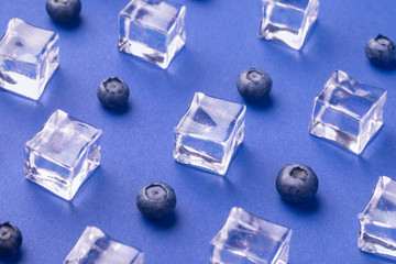 ice cubes with fresh blueberries on blue  background