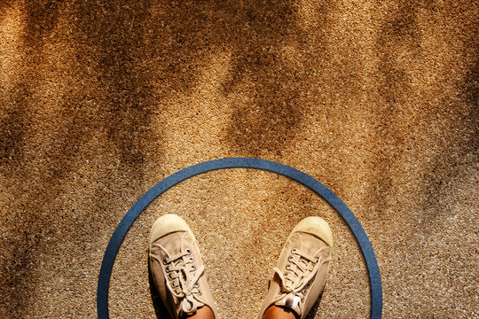 Comfort Zone Concept. Male On Sneaker Shoes Standing Inside A Circle Line, Top View, Grunge Dirty Concrete Floor With Sunlight As Background